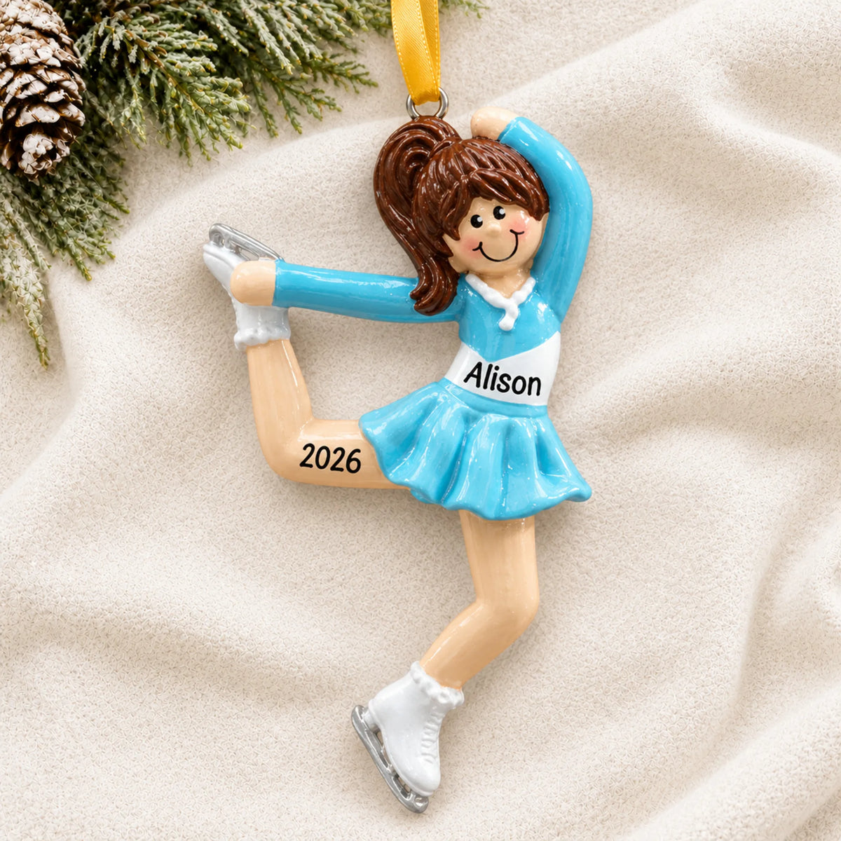 Personalized girl ice skater christmas ornament laid on a soft white knit blanket