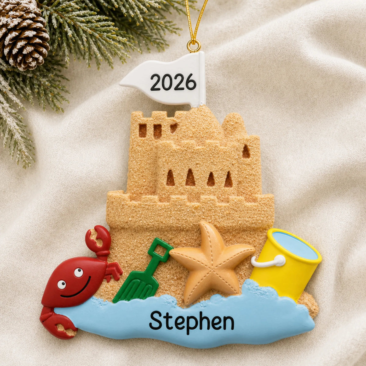 Personalized sand castle beach christmas ornament laid on a soft white knit blanket