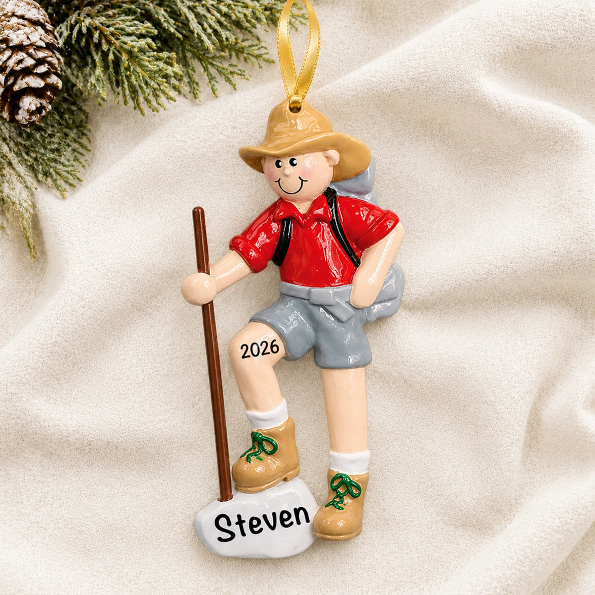 Personalized Hiker christmas ornament laid on a soft white knit blanket