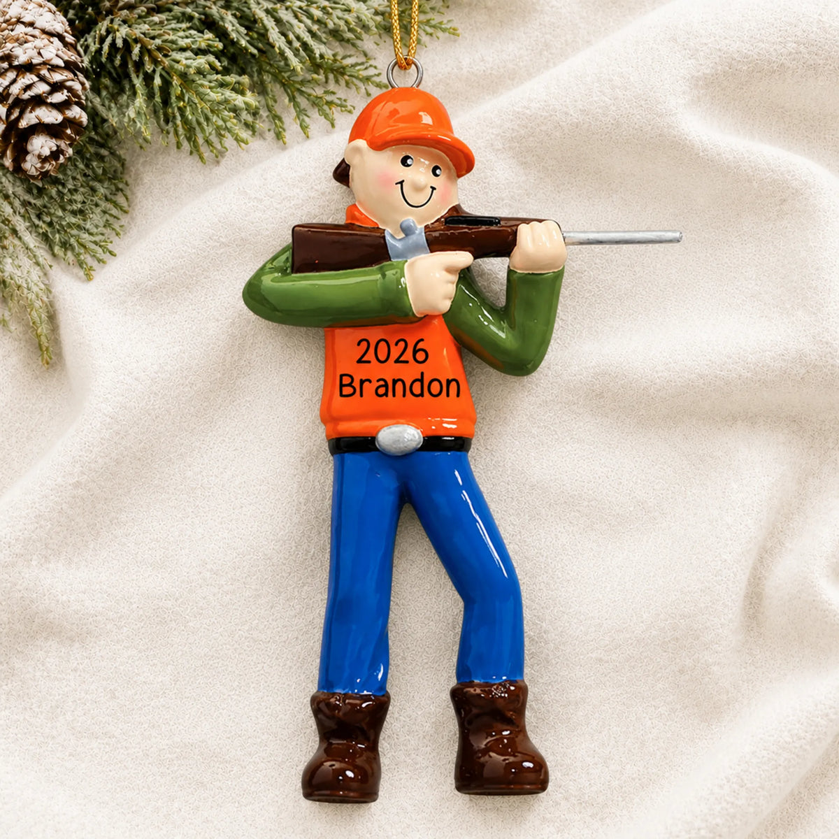 Personalized deer hunter christmas ornament laid on a soft white knit blanket