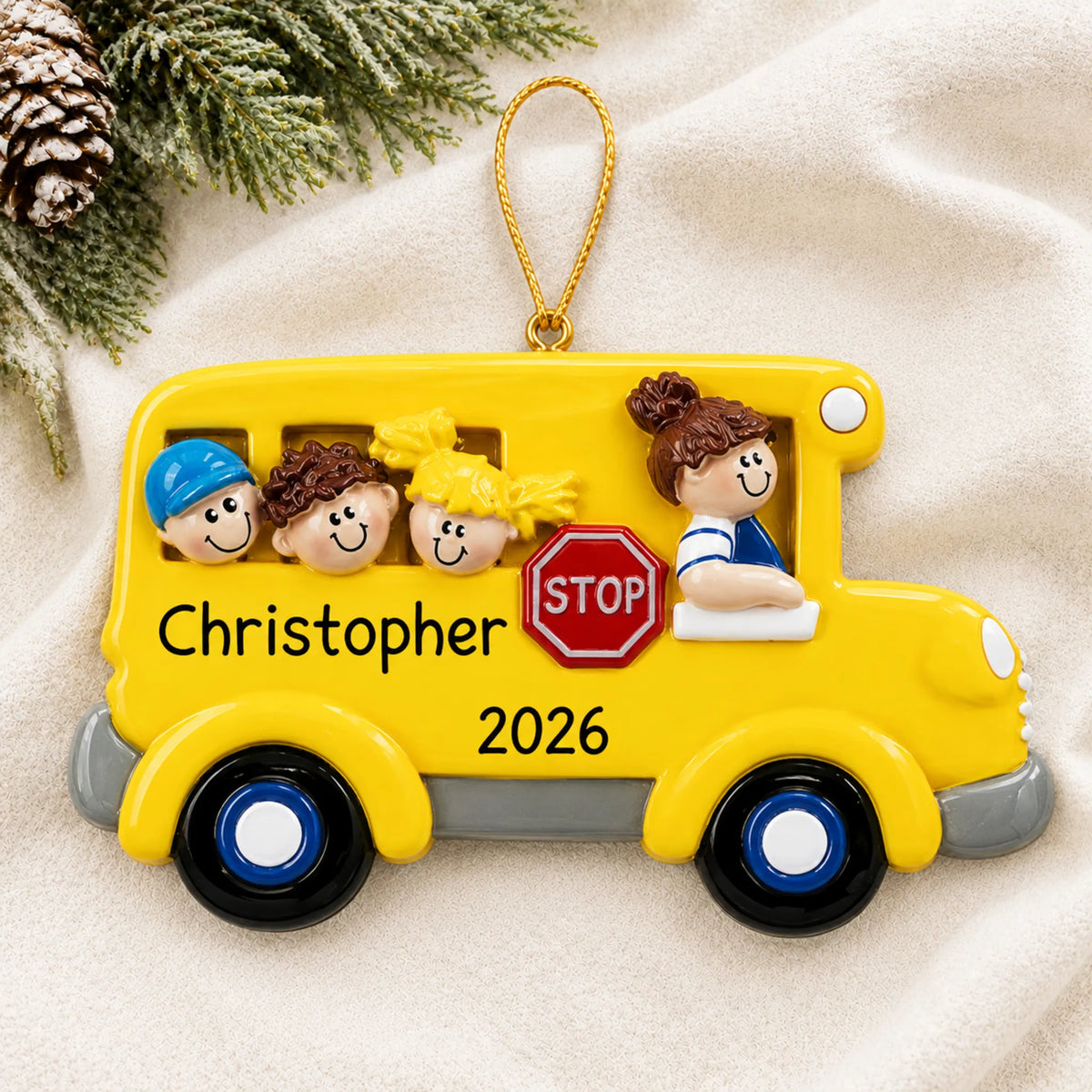 Personalized Kids School Bus christmas ornament laid on a soft white knit blanket