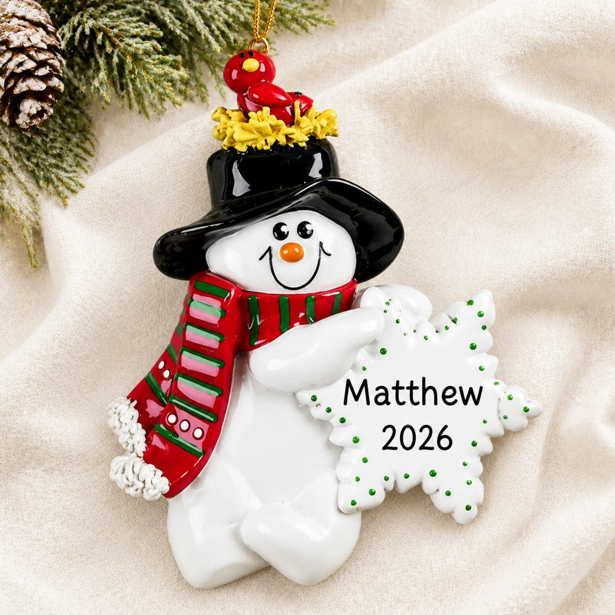 Personalized Birdsnest Snowman christmas ornament laid on a soft white knit blanket