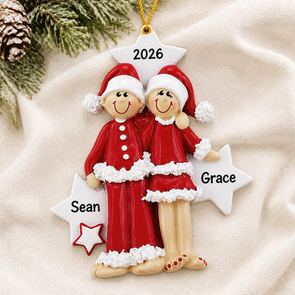 Personalized christmas pajama couple ornament laid on a soft white knit blanket
