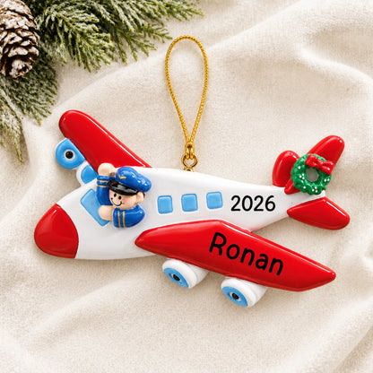 Personalized airplane pilot christmas ornament laid on a soft white knit blanket