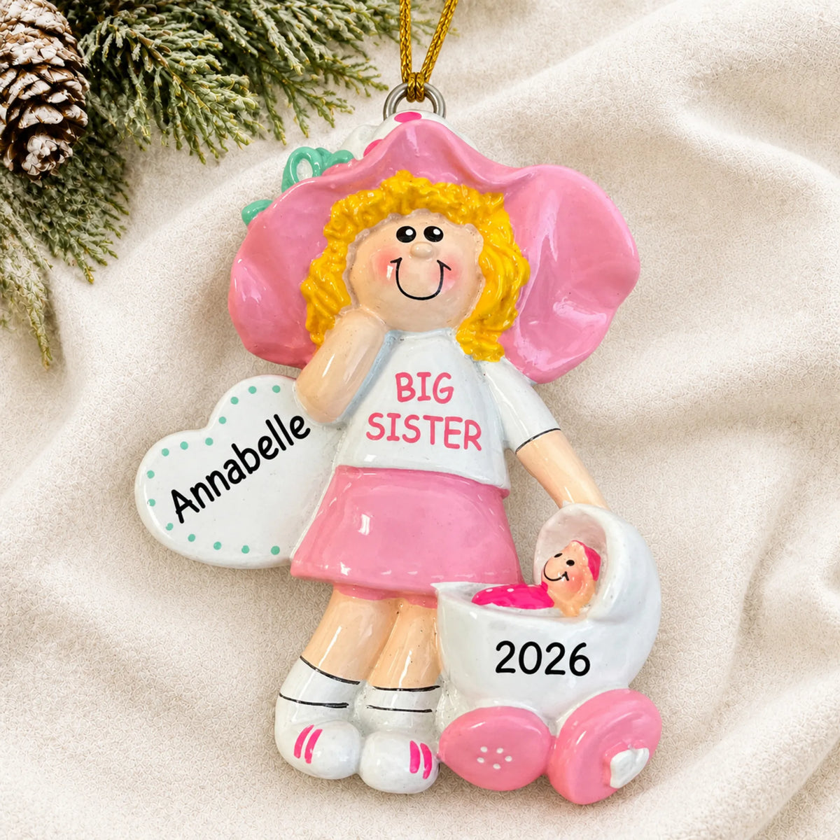 Personalized blonde big sister christmas ornament laid on a soft white knit blanket