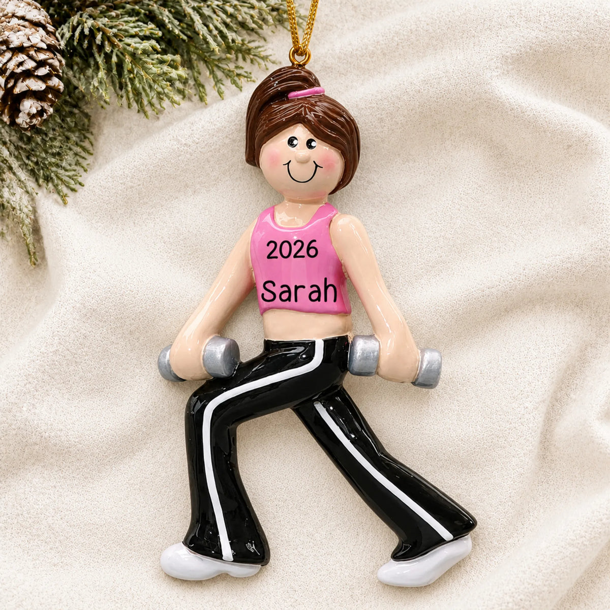 Personalized female fitness christmas ornament laid on a soft white knit blanket
