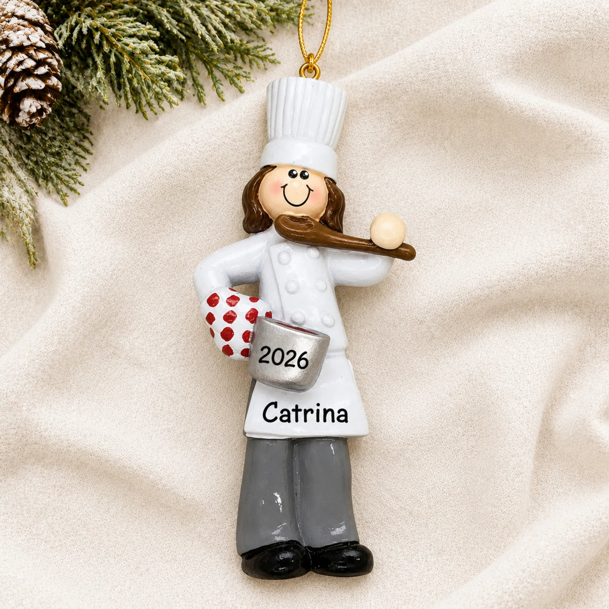 Personalized chef girl christmas ornament laid on a soft white knit blanket