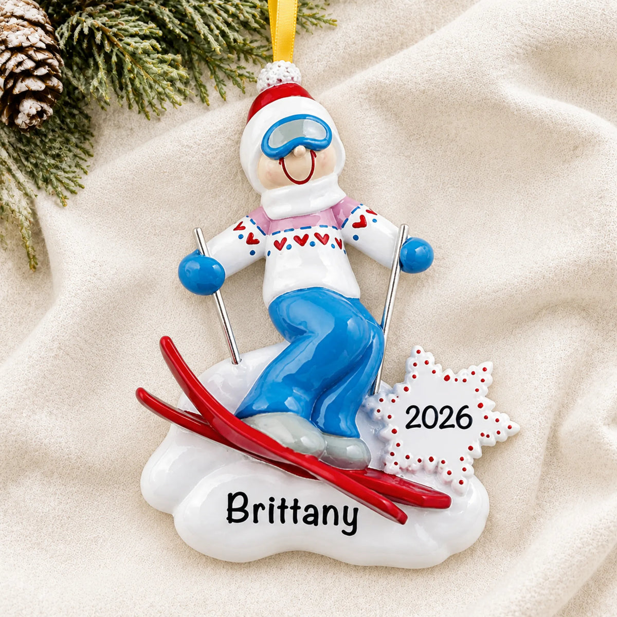 Personalized ski girl christmas ornament laid on a soft white knit blanket