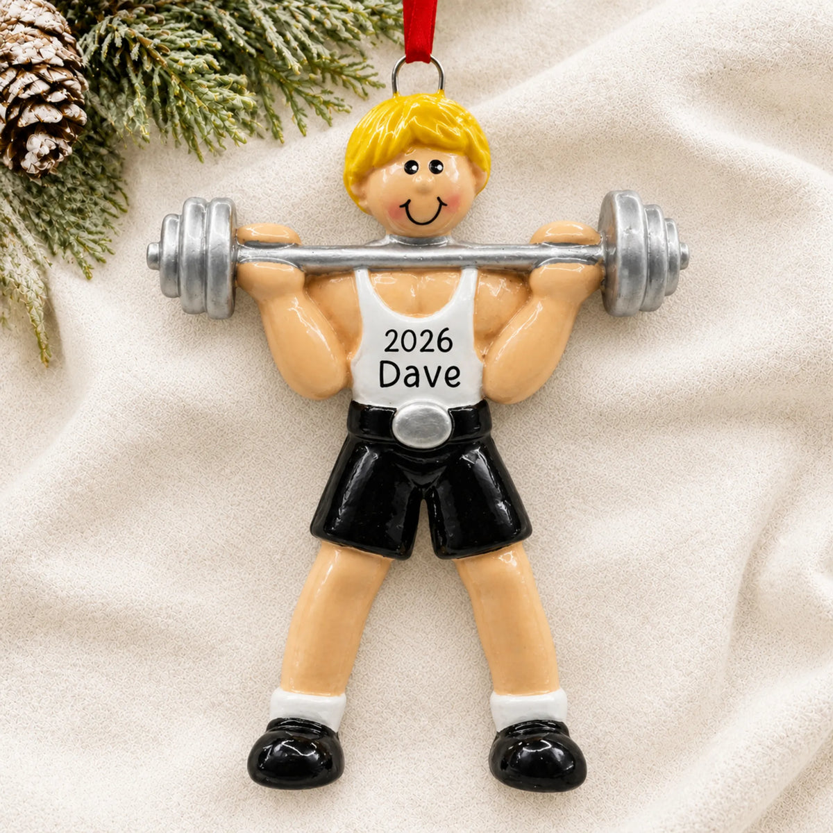 Personalized blonde weightlifter christmas ornament laid on a soft white knit blanket