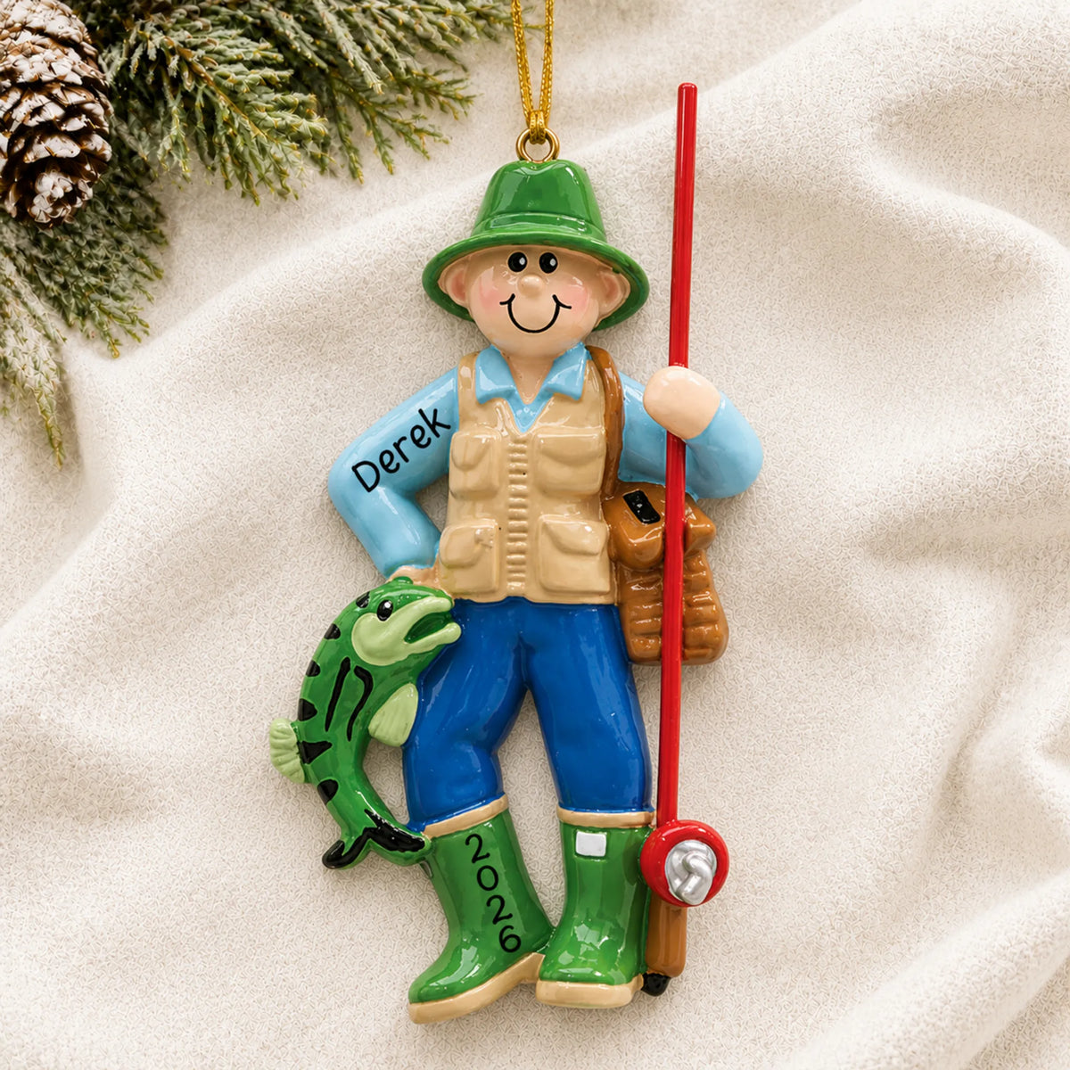 Personalized fly fisherman christmas ornament laid on a soft white knit blanket