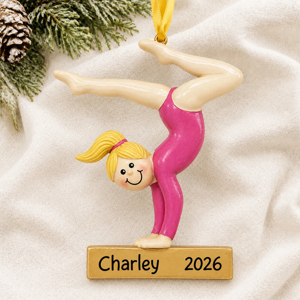 Personalized blonde gymnast balance beam christmas ornament laid on a soft white knit blanket