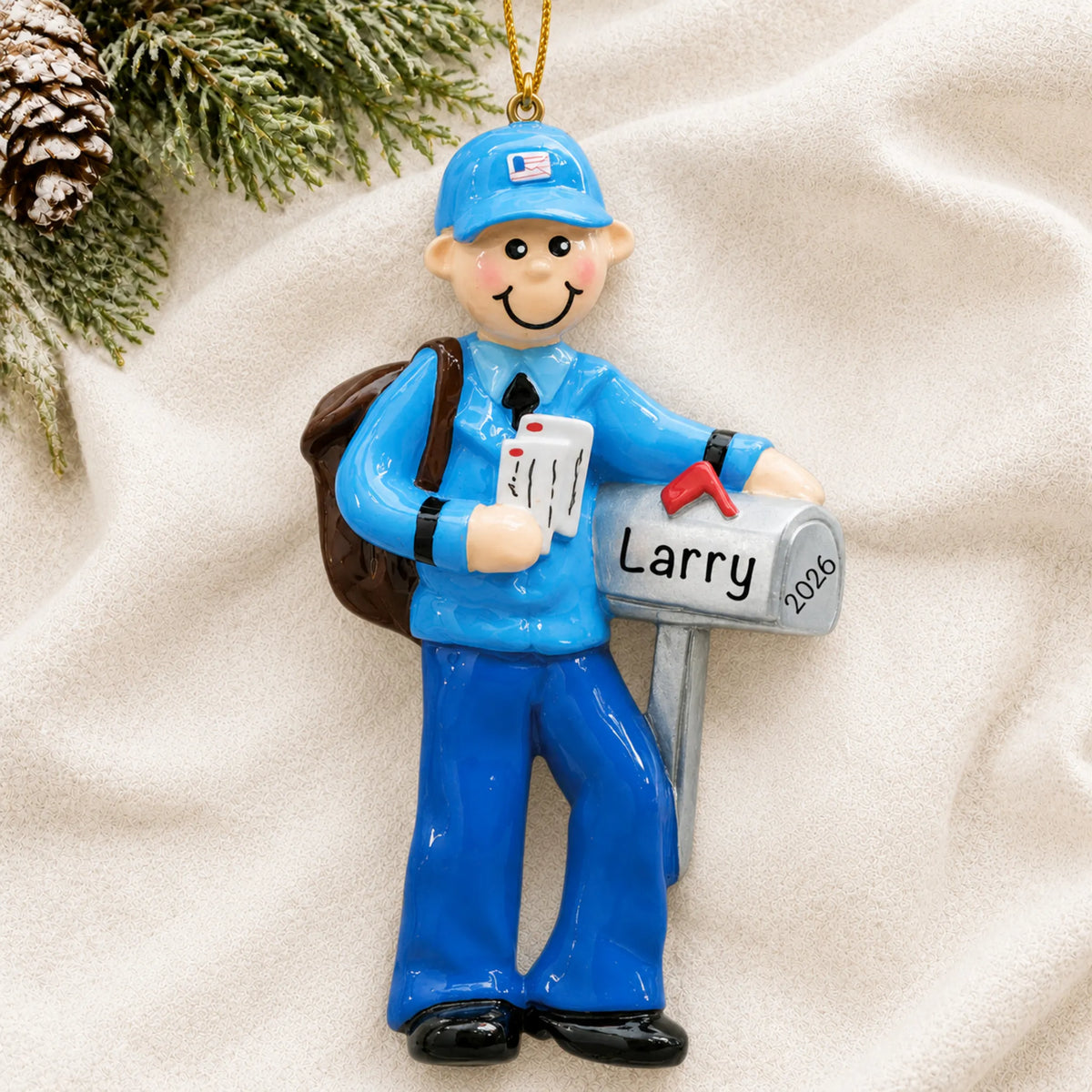 Personalized postal mail carrier christmas ornament laid on a soft white knit blanket
