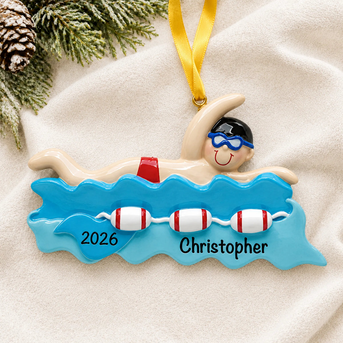 Personalized swim boy christmas ornament laid on a soft white knit blanket