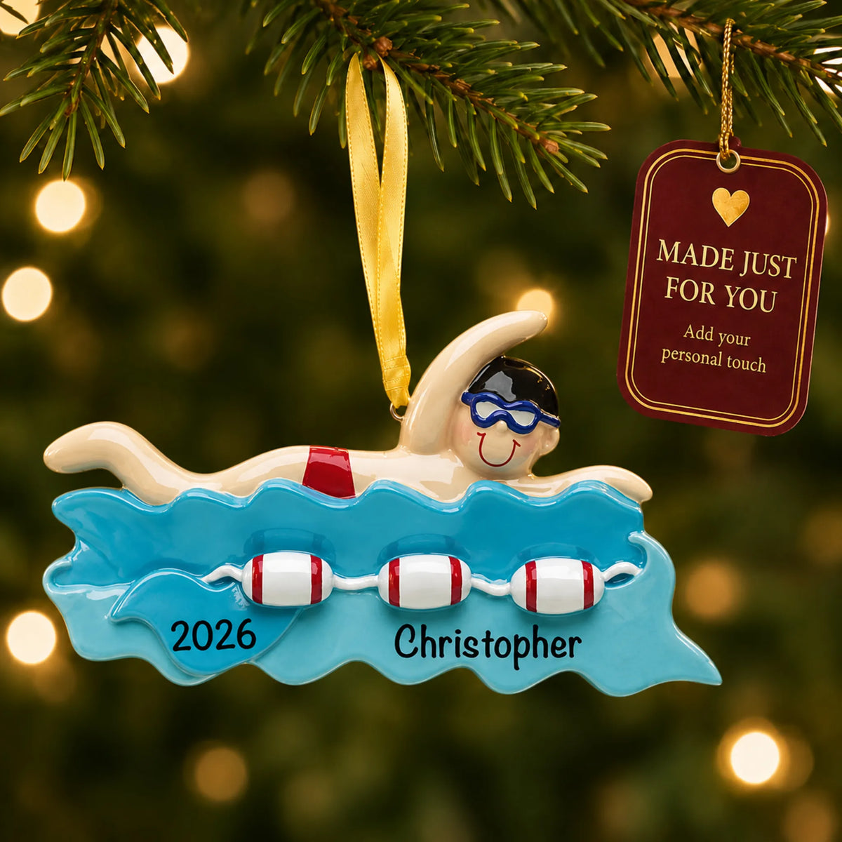 Swim boy christmas ornament hanging on a lit Christmas tree with a Made Just For You gift tag