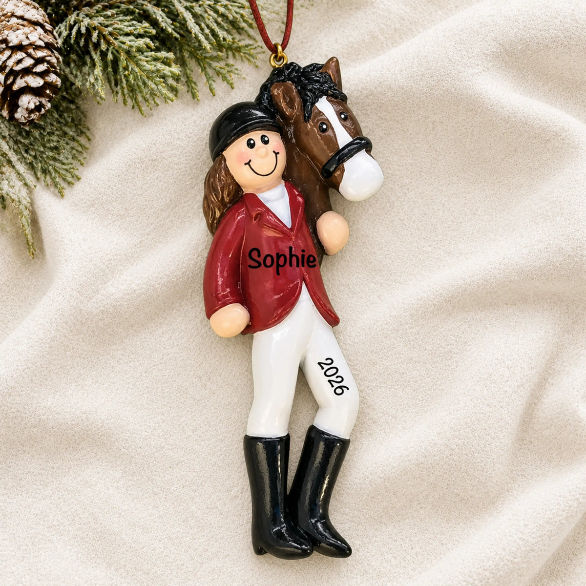 Personalized brunette horse riding girl christmas ornament laid on a soft white knit blanket