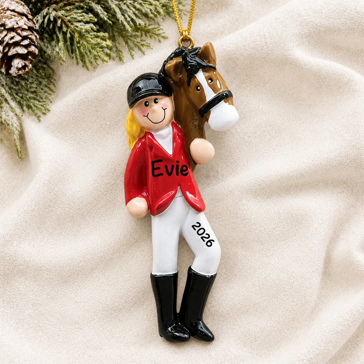 Personalized blonde horse riding girl christmas ornament laid on a soft white knit blanket
