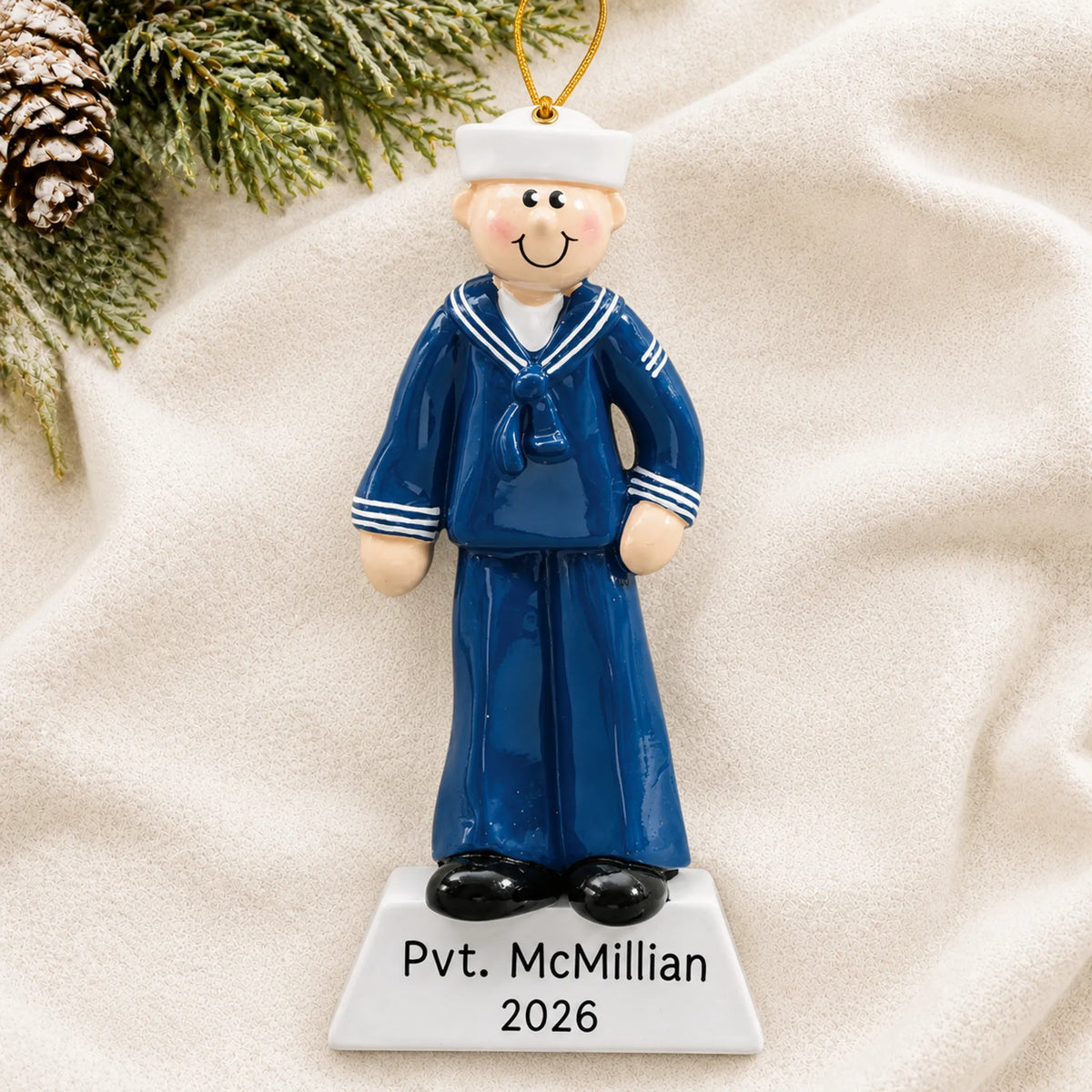 Personalized Navy sailor Christmas ornament shown on a soft white blanket