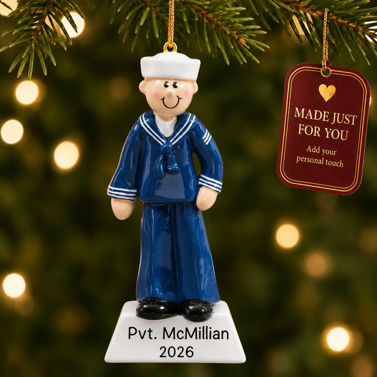 Personalized Navy sailor Christmas ornament hanging among tree lights with a Made Just For You tag
