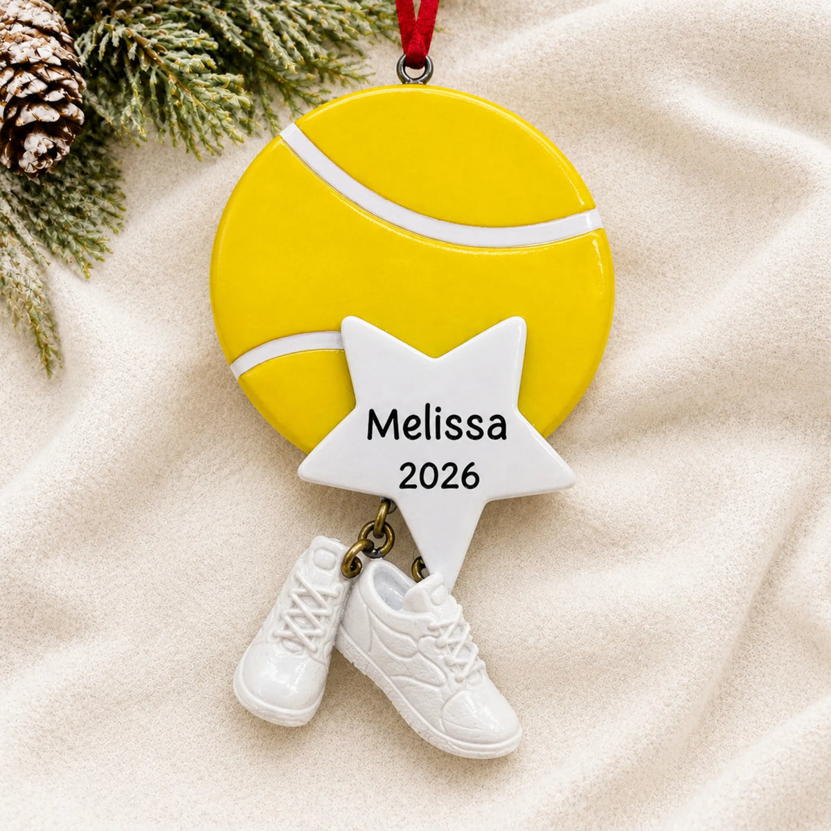 Personalized tennis star christmas ornament laid on a soft white knit blanket