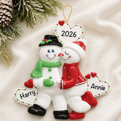 Personalized snow sweethearts couple christmas ornament laid on a soft white knit blanket