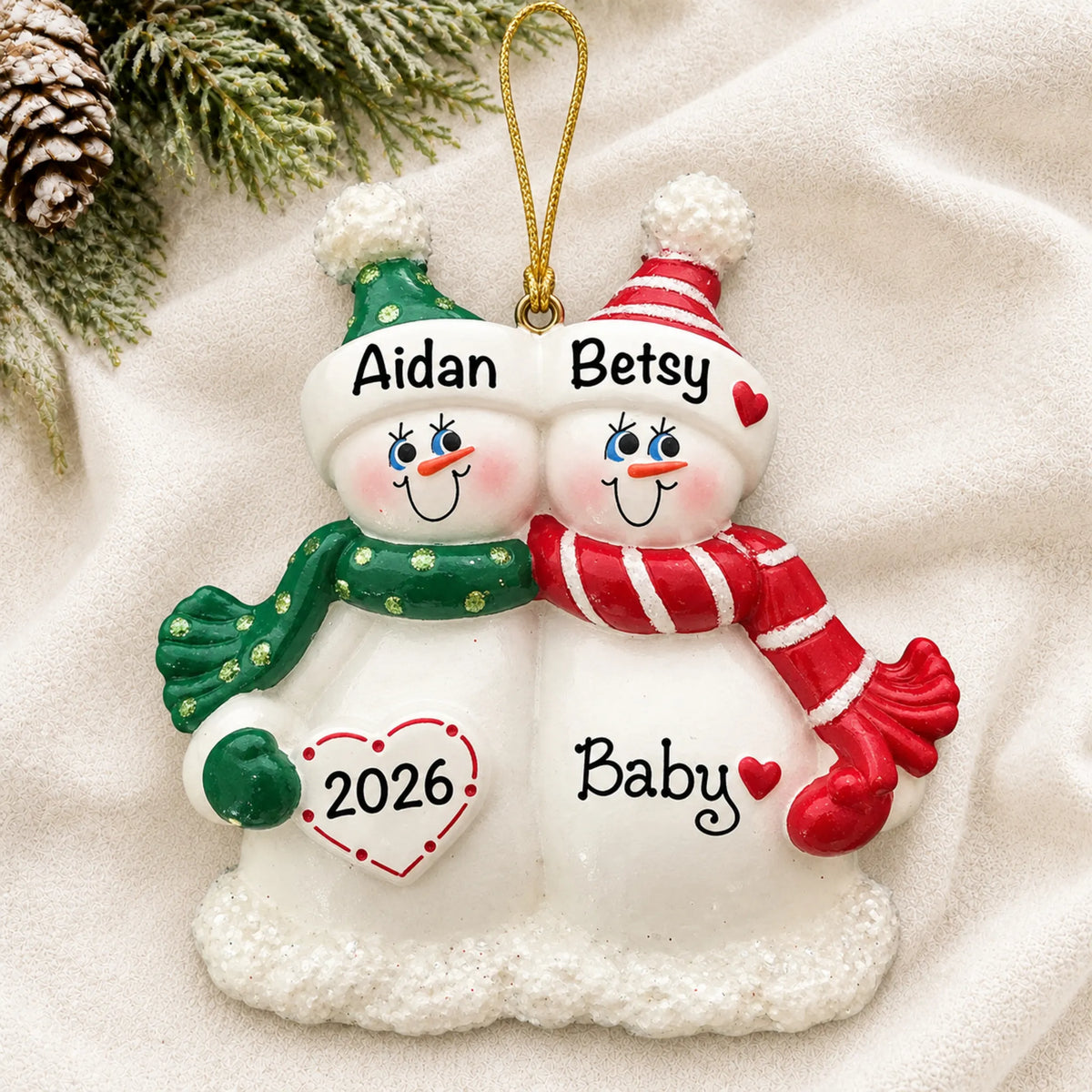 Personalized Snow Couple Expecting christmas ornament laid on a soft white knit blanket