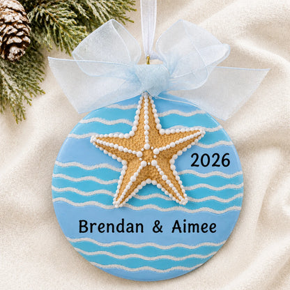 Personalized starfish beach christmas ornament laid on a soft white knit blanket