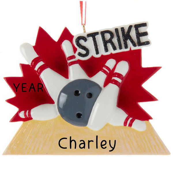 Personalized Christmas ornament showing a grey bowling ball hitting white pins with red stripes against a red background, with the lane base ready for engraving.
