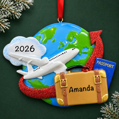 Personalized travel christmas ornament, a globe with an airplane, suitcase and passport, on a dark green pine background