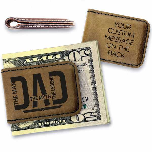Brown leather money clip with 'DAD' engraving on a dollar bill, with another similar product in the background.