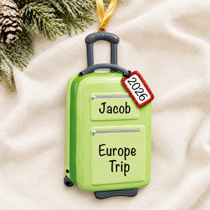 Personalized green travel suitcase christmas ornament laid on a soft white knit blanket