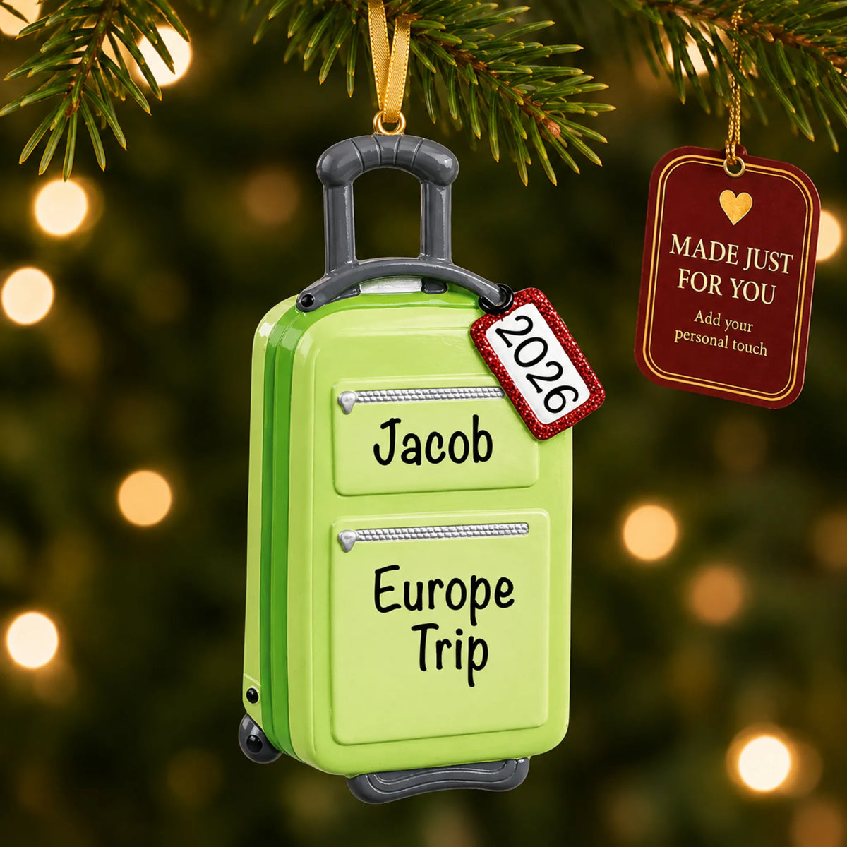 Green travel suitcase christmas ornament hanging on a lit Christmas tree with a Made Just For You gift tag