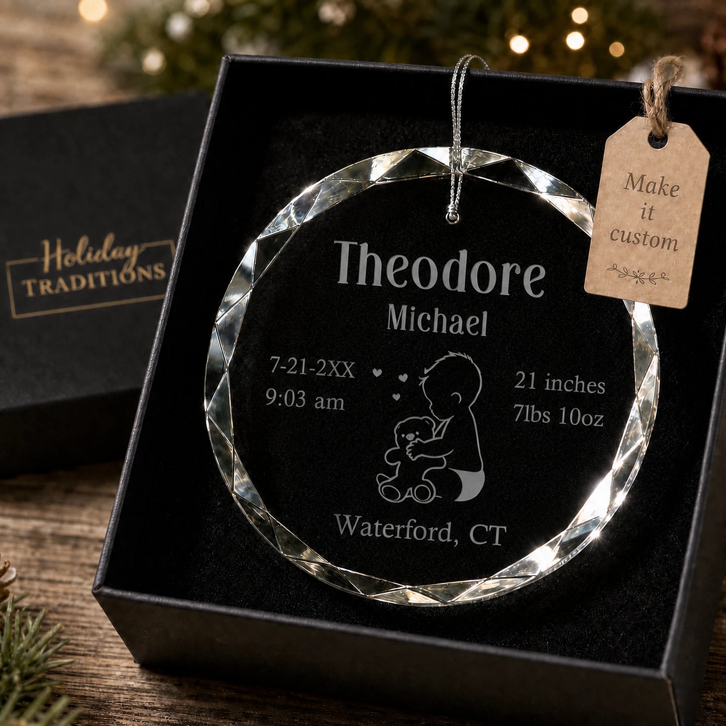 Baby's first Christmas personalized glass ornament with a baby and teddy bear design, laser engraved with baby's name, birth stats and birthplace, shown in its black gift box