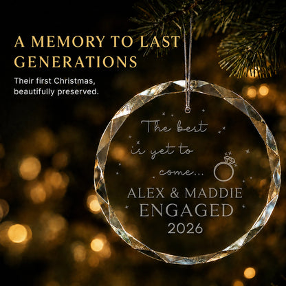 Personalized The Best Is Yet to Come engagement ornament in K9 optical glass hanging on a lit tree, engraved with the couple's names and engagement year