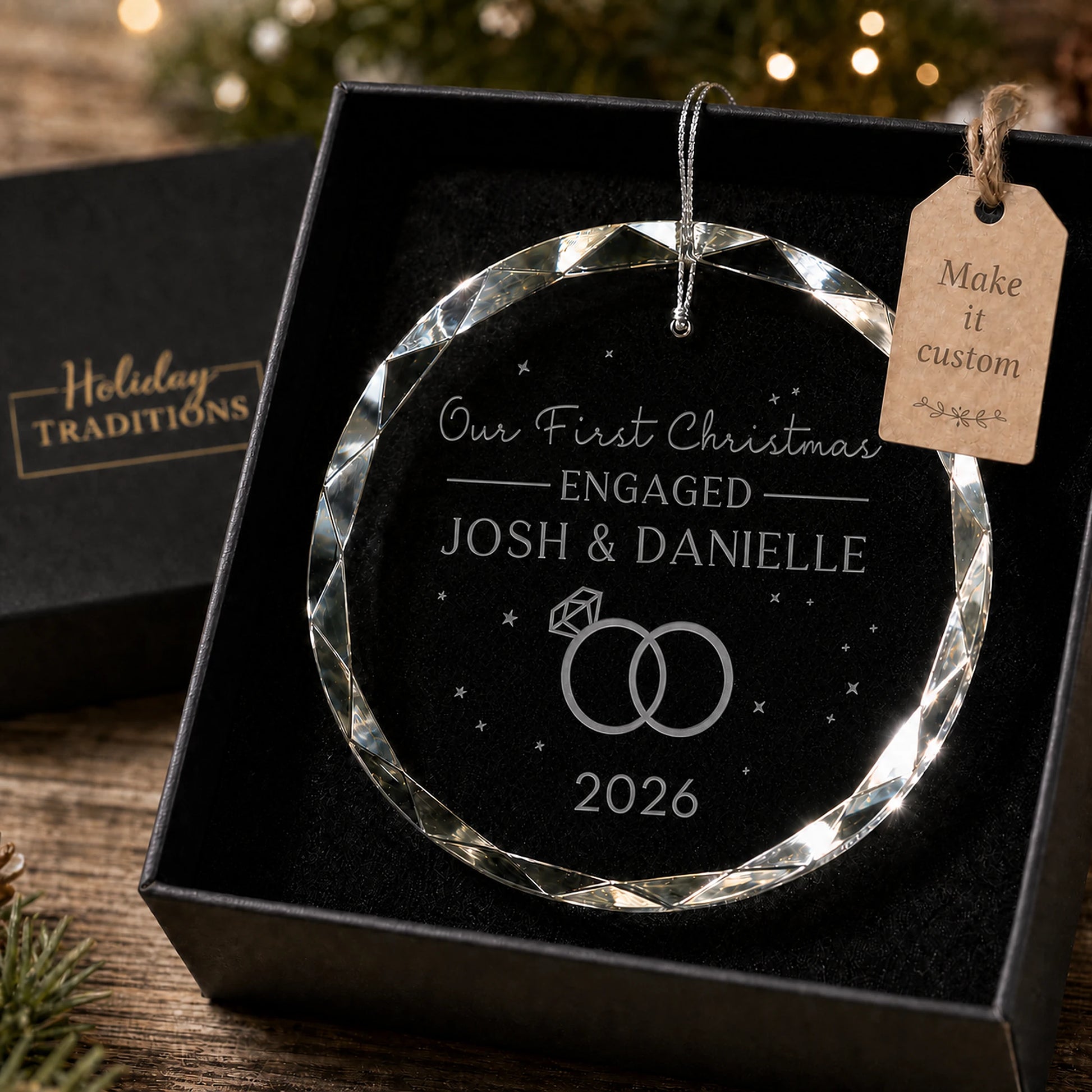 Our First Christmas Engaged personalized glass ornament with two rings, laser engraved with the couple's names and year, shown in its black gift box