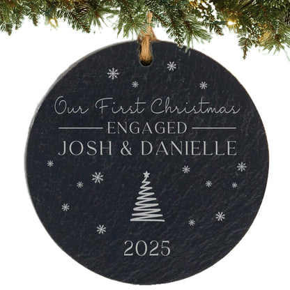 Black slate ornament engraved with “Our First Christmas Engaged,” couple’s names, snowflakes, and year.