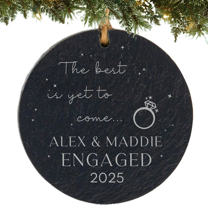 Round slate ornament engraved with “The best is yet to come,” engagement ring graphic, couple’s names, and year.
