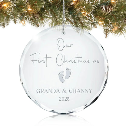 Personalized glass ornament engraved with “Our First Christmas as Granda & Granny 2025” and baby footprints design, hanging on a Christmas tree.