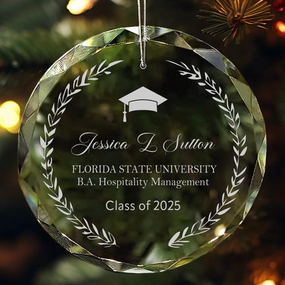 Personalized glass graduation ornament with laurel wreath design, engraved name, school, and “Class of 2025” hanging on a Christmas tree.