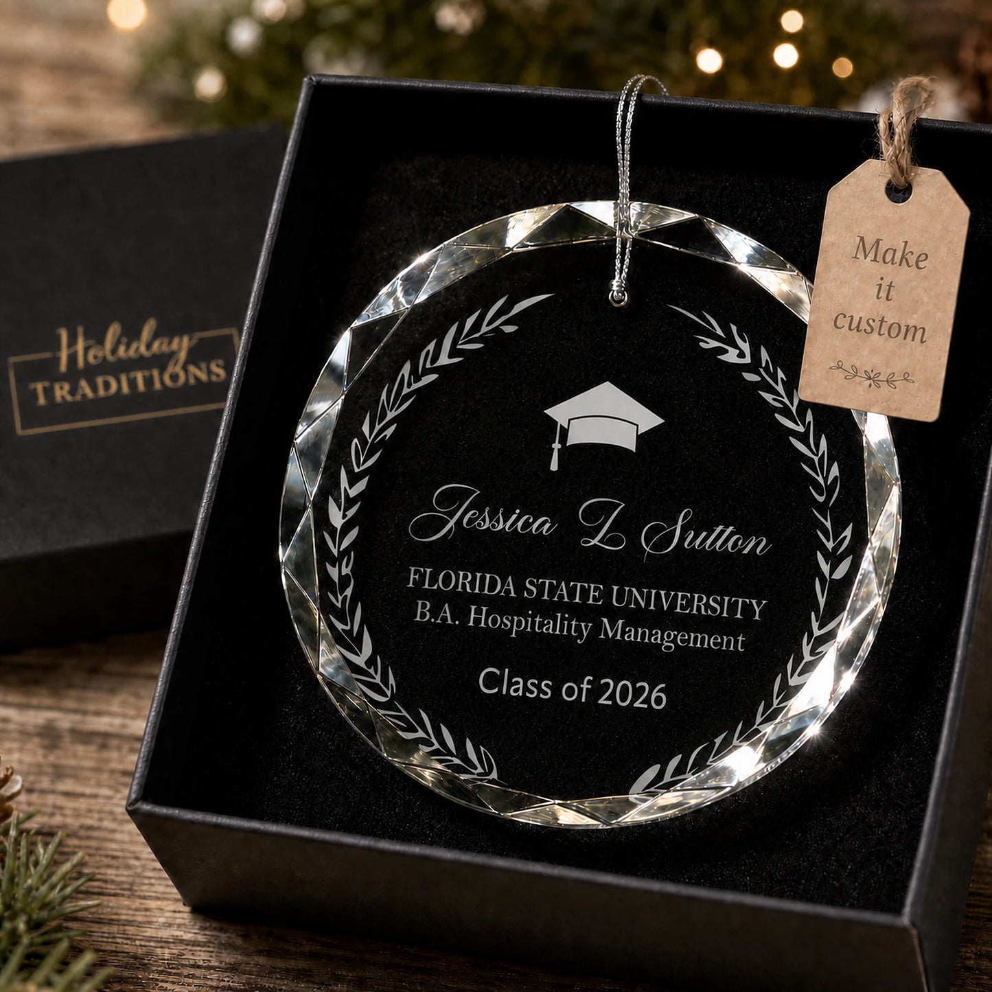 Laurel wreath graduation personalized glass ornament, laser engraved with a graduation cap, name, school, degree and class year inside a laurel wreath, shown in its black gift box