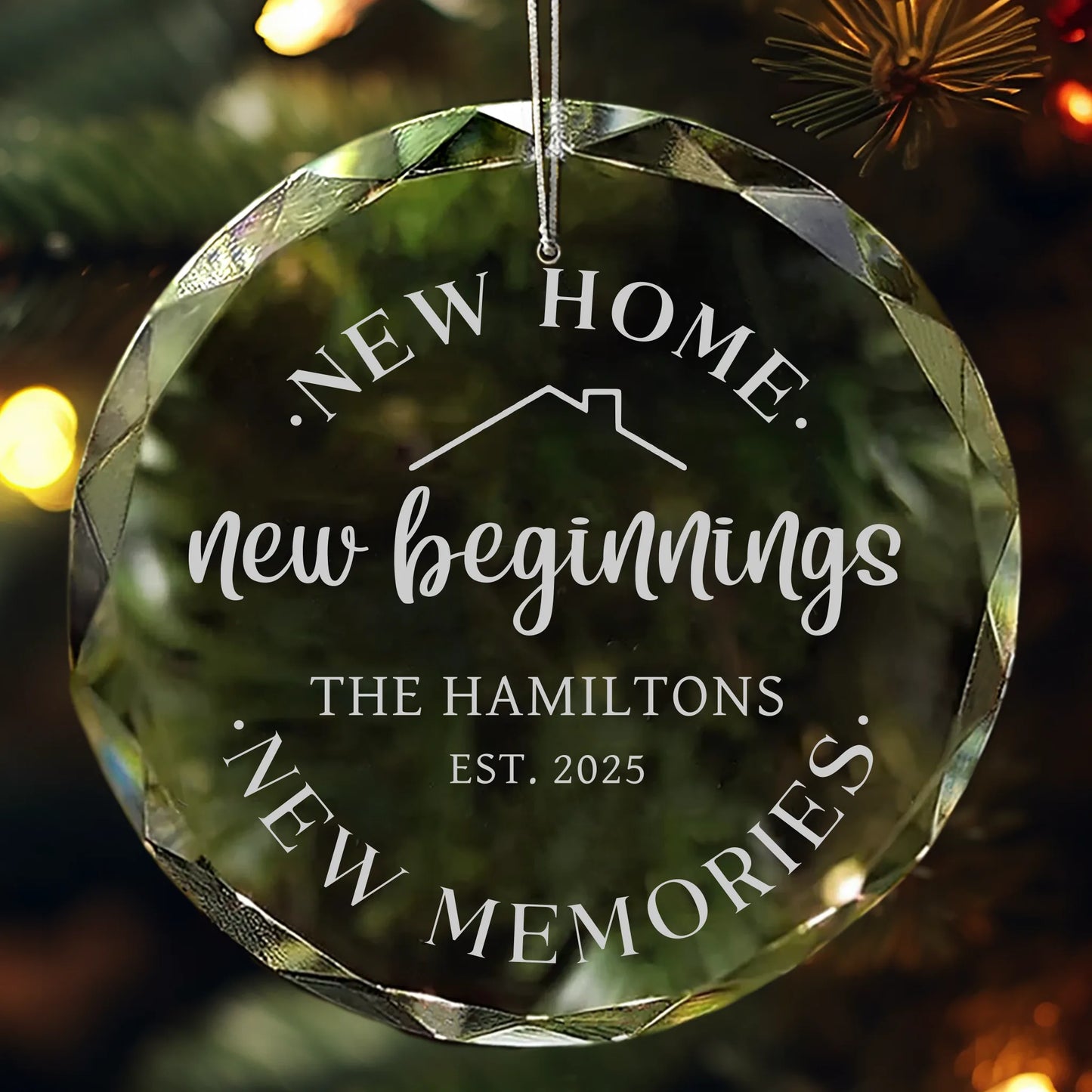 Personalized glass ornament reading “New Home, New Beginnings, New Memories” hanging on a Christmas tree.