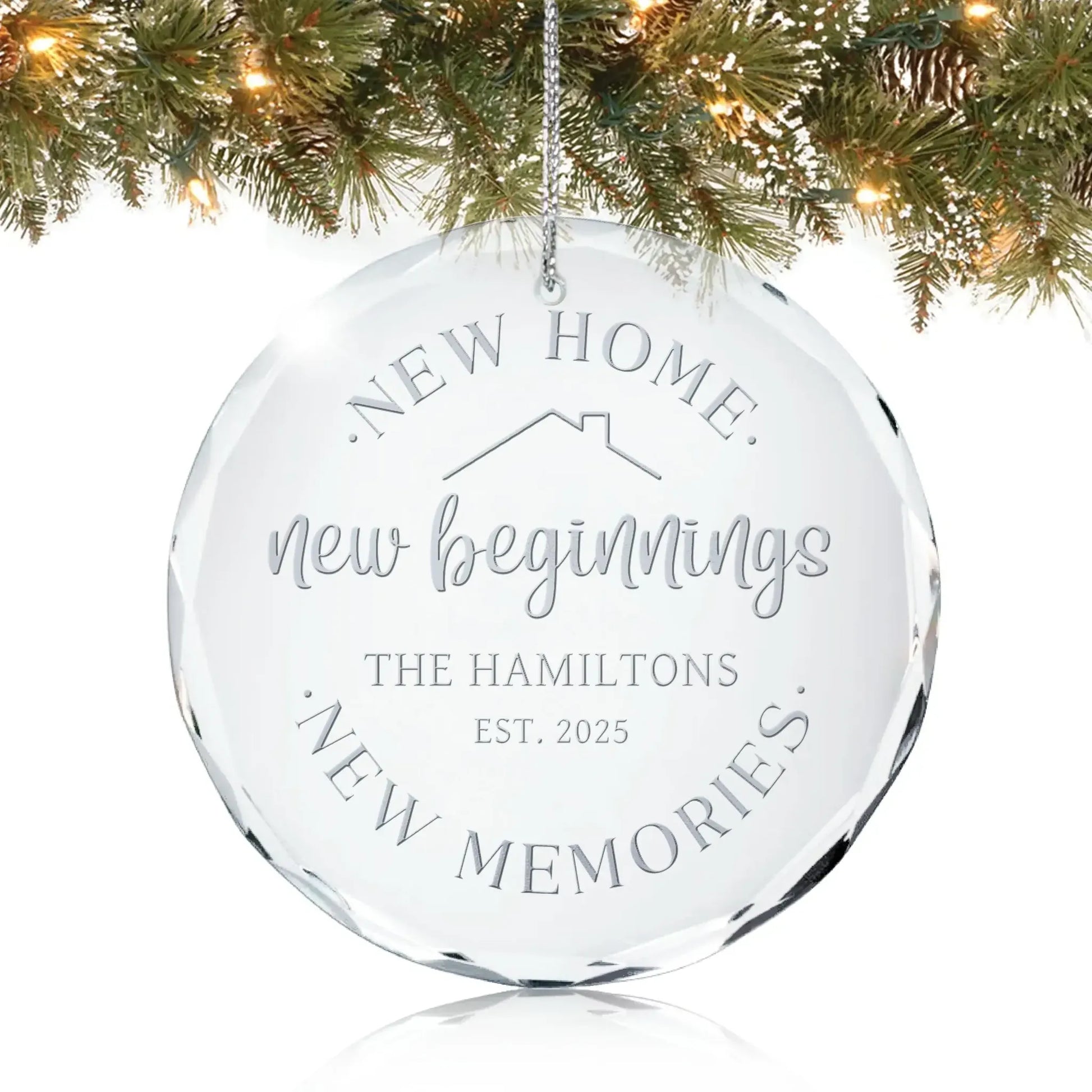 Personalized glass ornament reading “New Home, New Beginnings, New Memories” hanging on a Christmas tree.