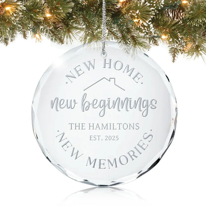 Personalized glass ornament reading “New Home, New Beginnings, New Memories” hanging on a Christmas tree.