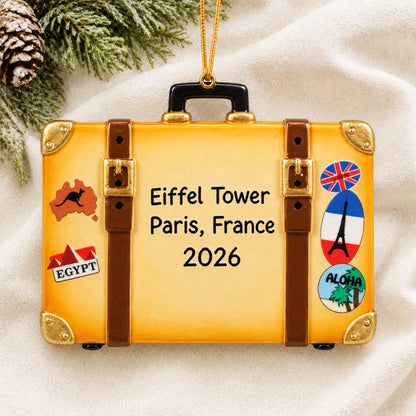 Personalized tan travel suitcase christmas ornament laid on a soft white knit blanket