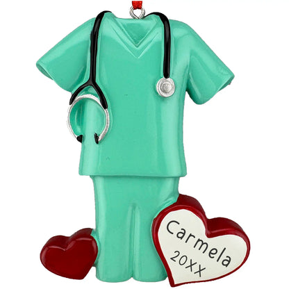 Personalized ornament in the shape of a medical scrub set with a stethoscope and heart-shaped tag on a white background
