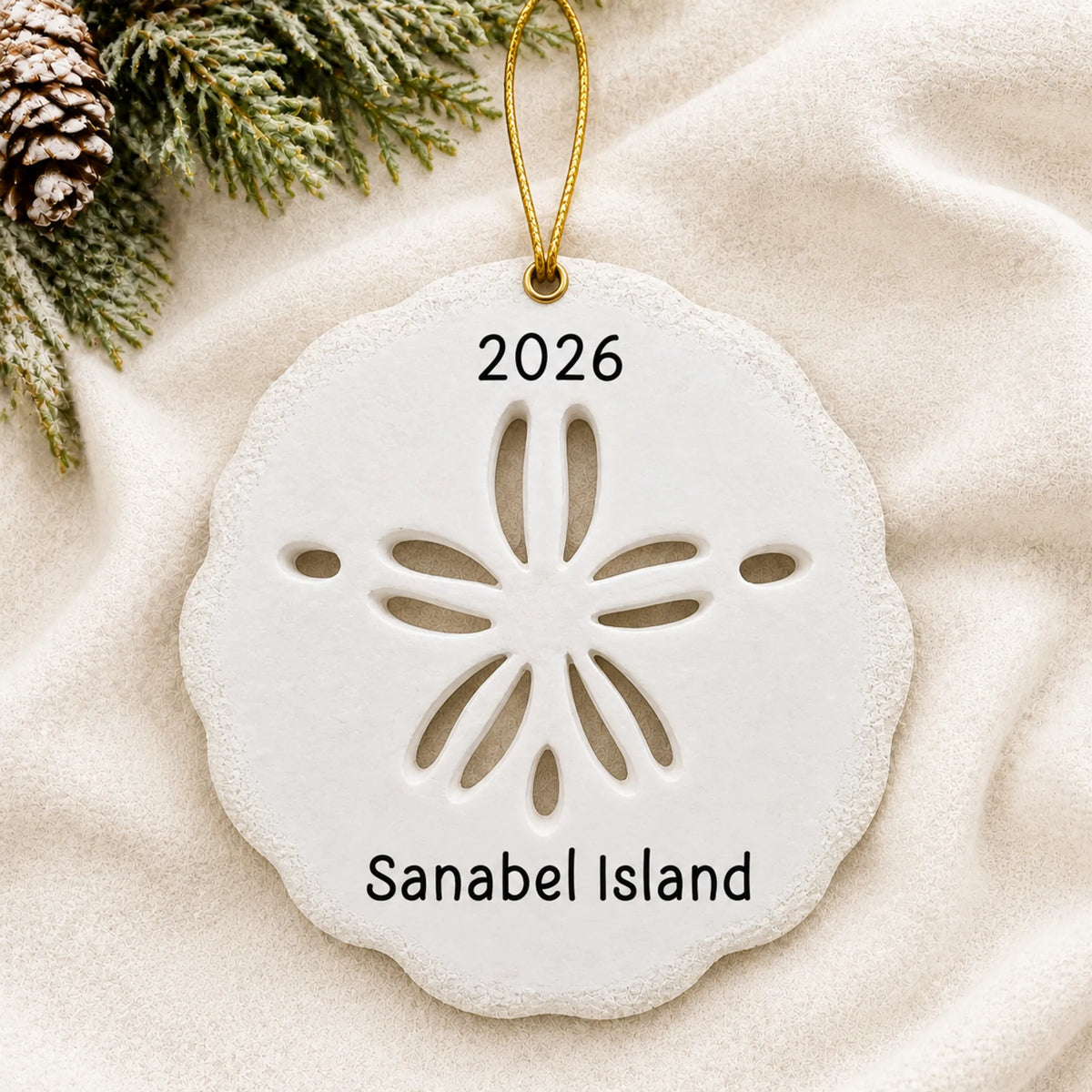 Personalized sand dollar christmas ornament laid on a soft white knit blanket