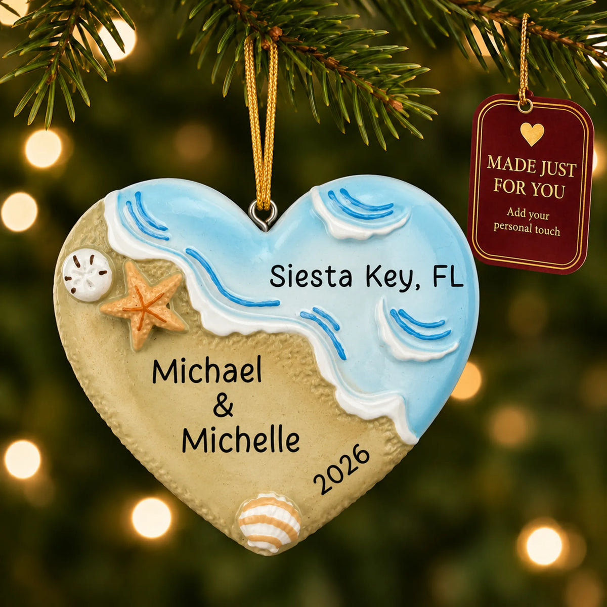 Name in sand beach christmas ornament hanging on a lit Christmas tree with a Made Just For You gift tag