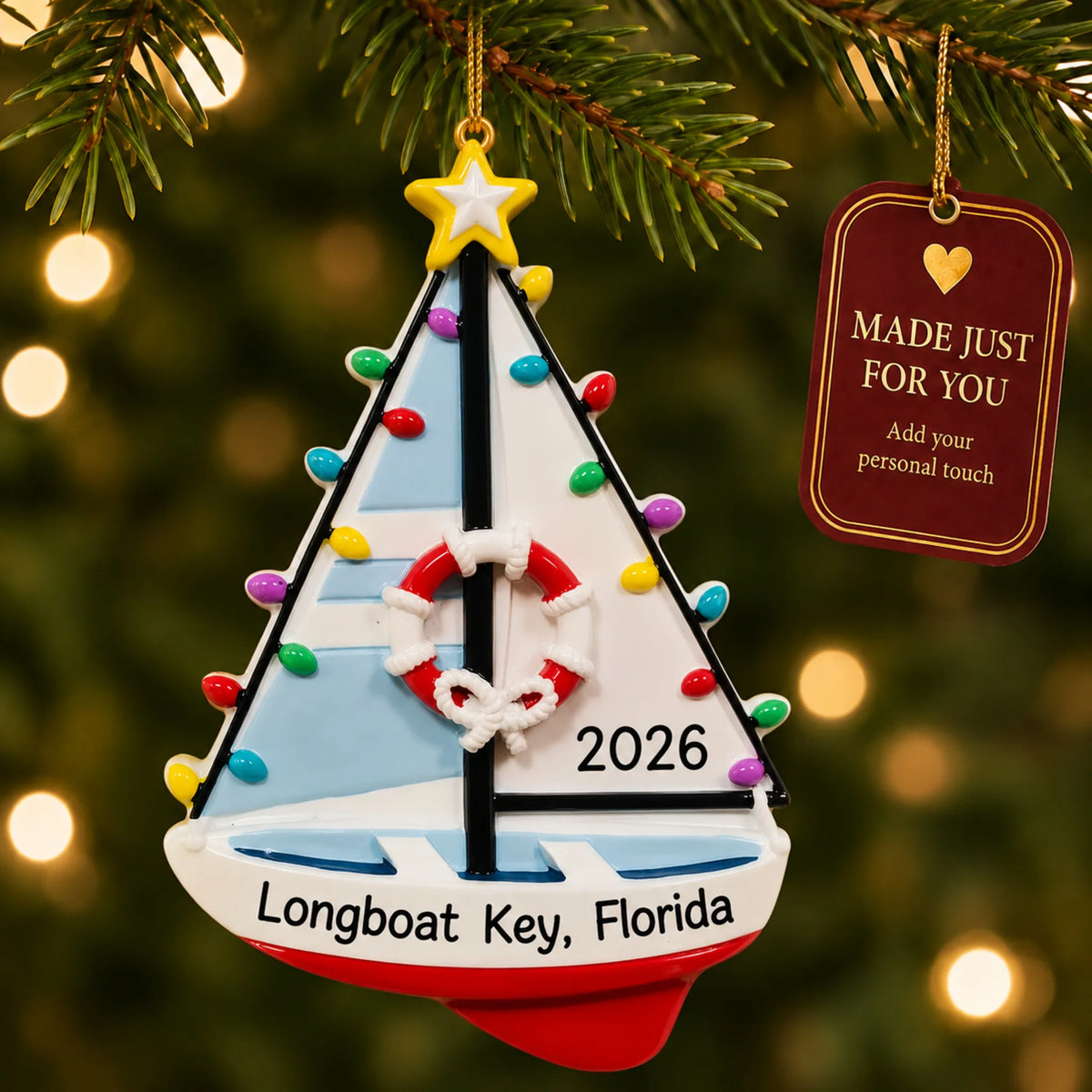 Lighted sailboat christmas ornament hanging on a lit Christmas tree with a Made Just For You gift tag