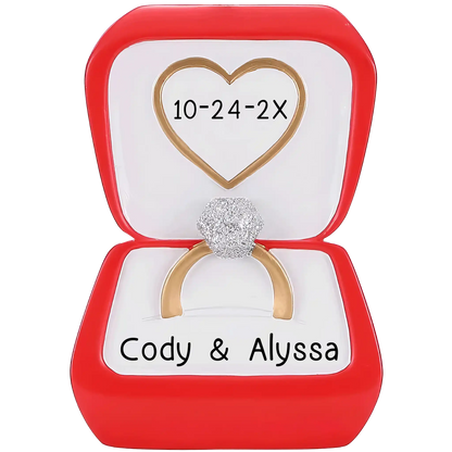 Personalized Christmas ornament shaped like an open red engagement ring box featuring a gold ring with a sparkling simulated diamond, ready for custom name and date engraving.