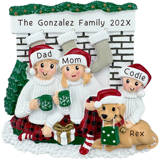 Family of 3 with dog personalized Christmas ornament at fireplace, wearing Santa hats and matching pajamas