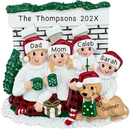Family of 4 with dog personalized Christmas ornament featuring matching pajamas and mugs by the fireplace